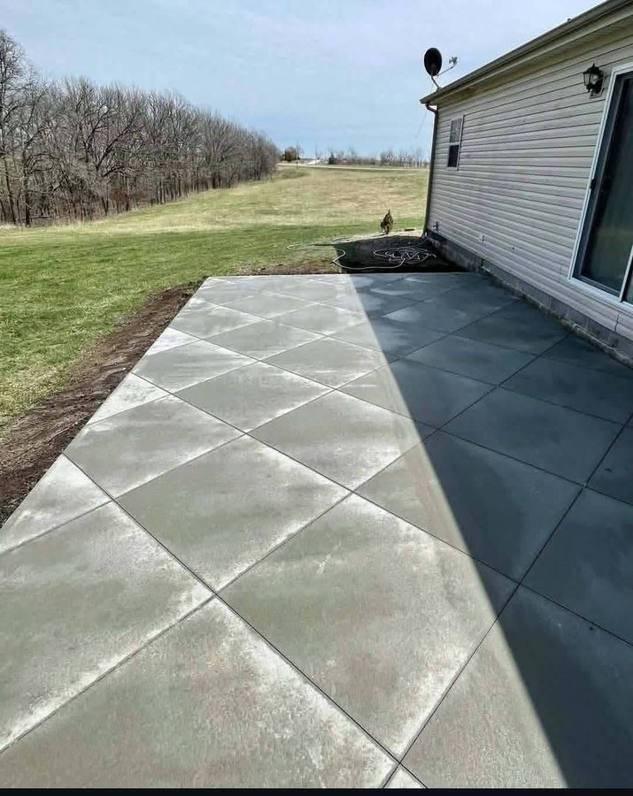 Large troweled concrete patio with a diamond score pattern behind a house